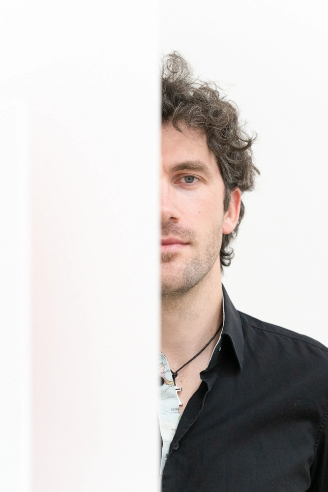 Business Headshot Duo-Klak – Künstlerporträt eines Musikers halb verdeckt hinter weißer Wand.