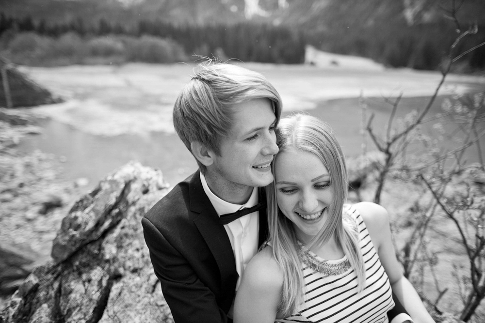 Verliebtes Paar beim Paarshooting am See auf Felsen sitzend, Paarfotograf Villach Kärnten Österreich