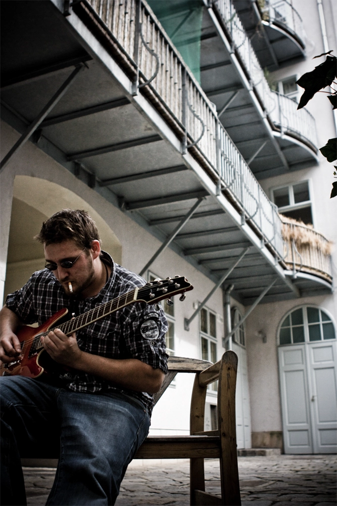 Business Porträt Gitarrist mit E‑Gitarre im Wiener Innenhof, urbanes Musikerporträt.